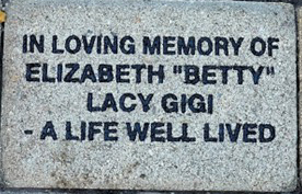 Example of an engraved brick at Santa Teresita reading "IN LOVING MEMORY OF ELIZABETH 'BETTY' LACY GIGI - A LIFE WELL LIVED"
